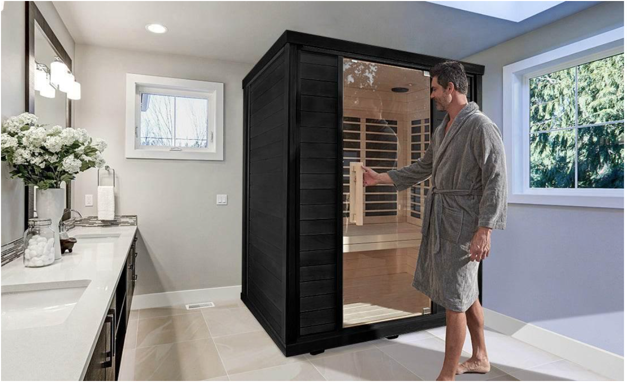 Man in bathrobe opening a black indoor infrared sauna.
